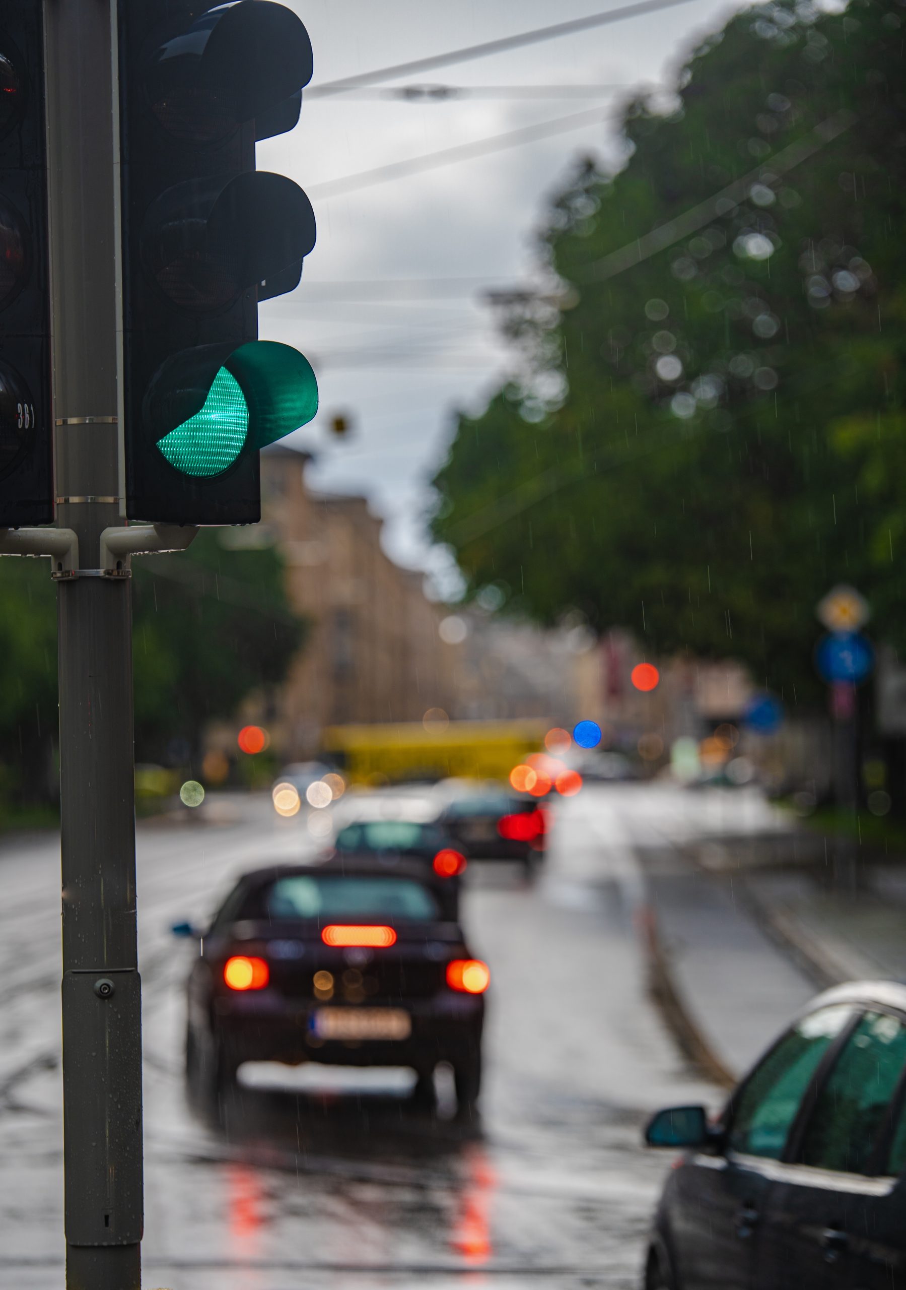 green traffic light during the rain, cars drive by